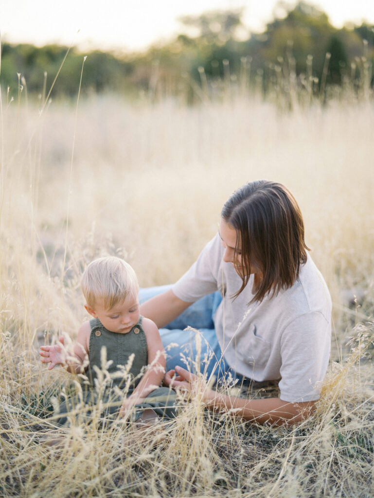 Mom playing with his baby in field 