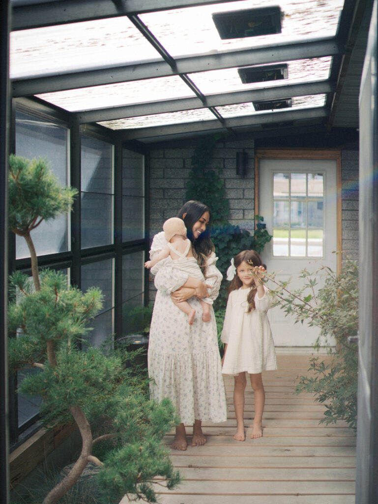 A mom standing in their house with her two daughters. 